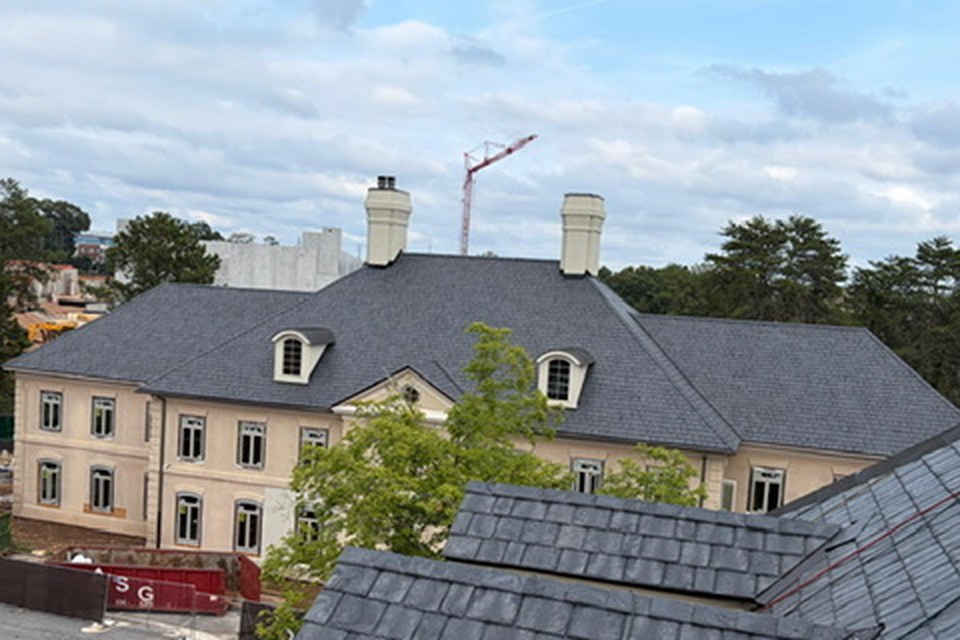 Brava composite slate on a new-construction estate in Atlanta - steep hips, dormers and tall chimneys.
