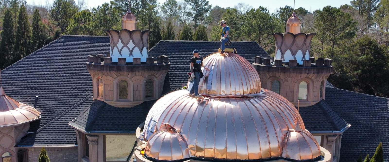 Mosaic crew installing hand-formed standing seam copper domes and turret caps on a luxury home