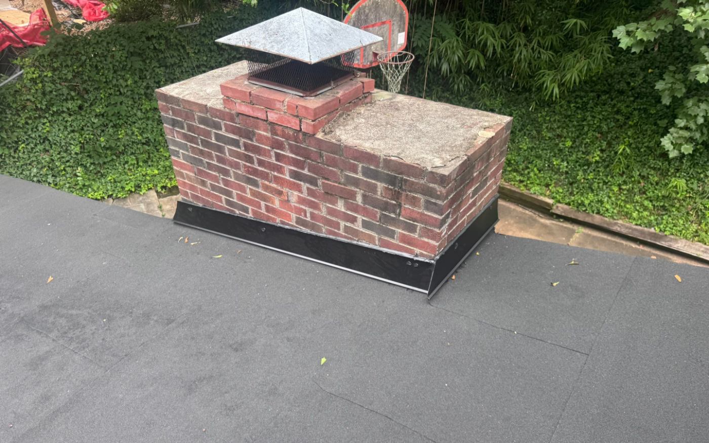 New metal counter-flashing where the modified bitumen meets the chimney - the detail that keeps a low-slope roof dry.