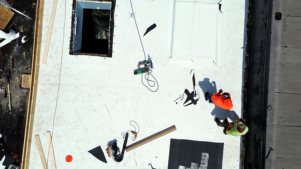 Overhead view mid-install: TPO membrane seams being hot-air welded