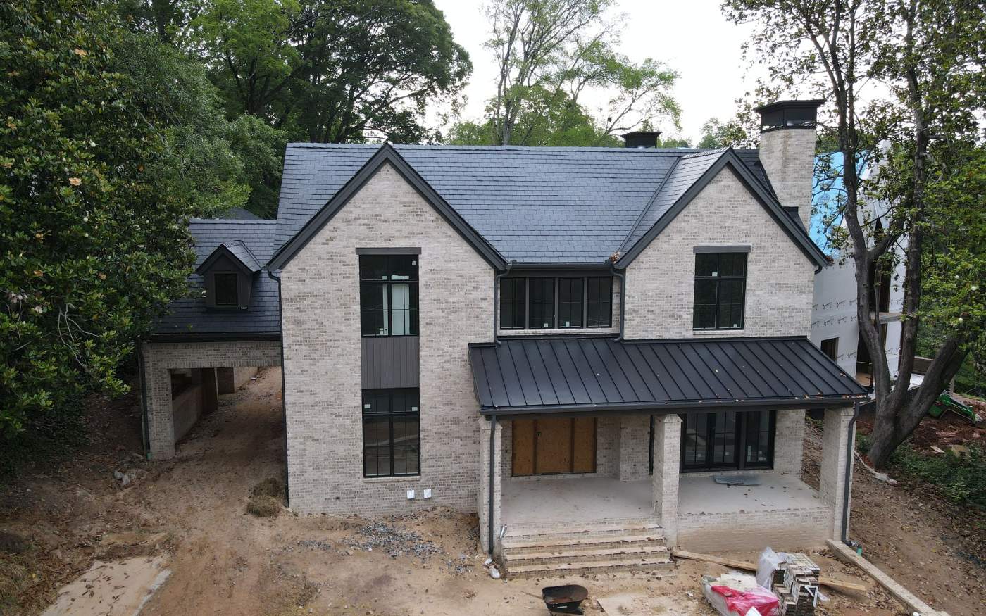 Natural slate roof with standing seam metal accents on a stone home