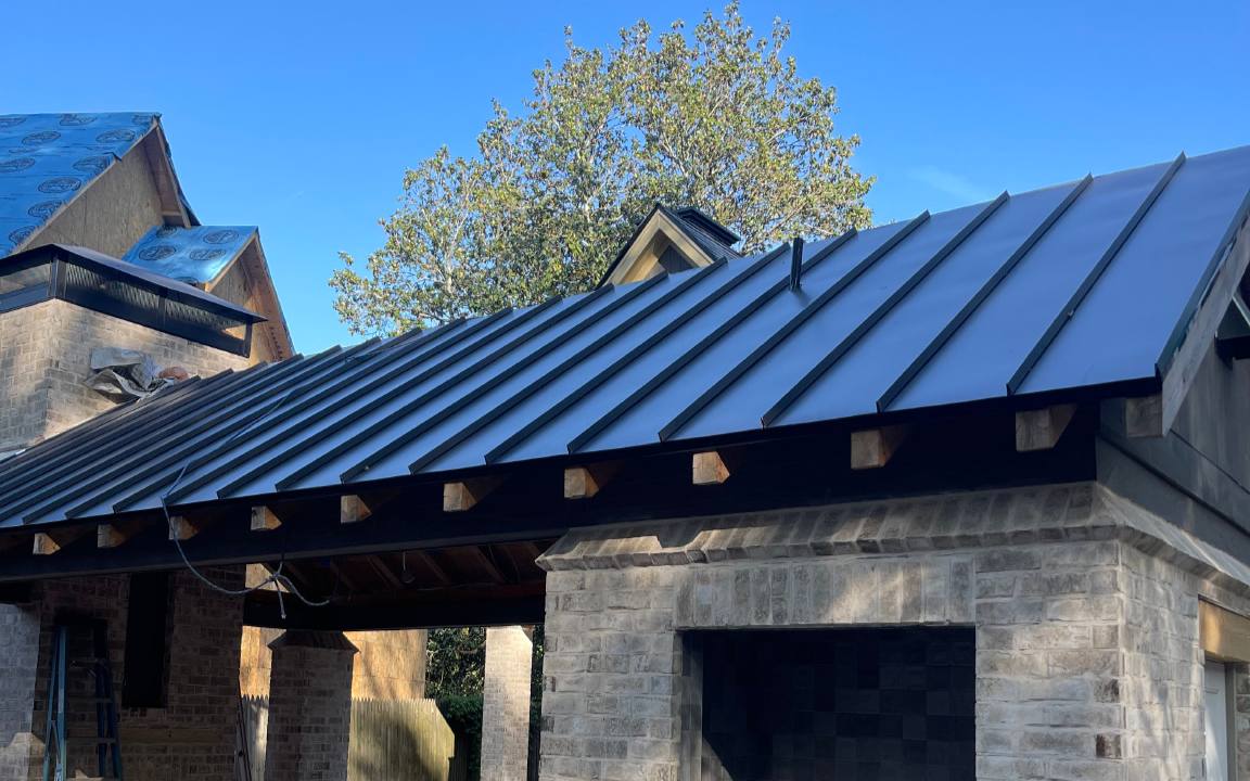 Black standing seam metal roof over a stone home in metro Atlanta