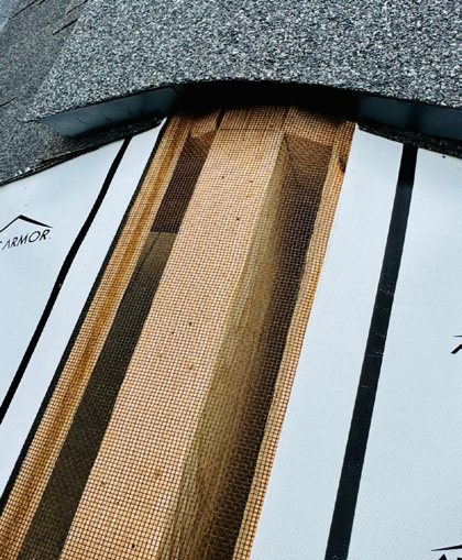 Attic Armor mesh barrier being installed along the open ridge of a shingle roof, before the ridge vent goes on.