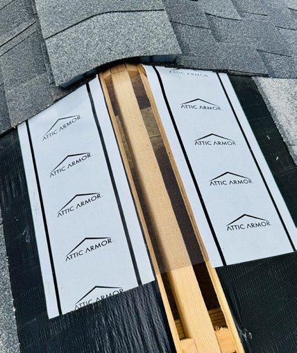 Attic Armor underlayment and ridge barrier installed on a roof ridge, with Attic Armor branding visible.